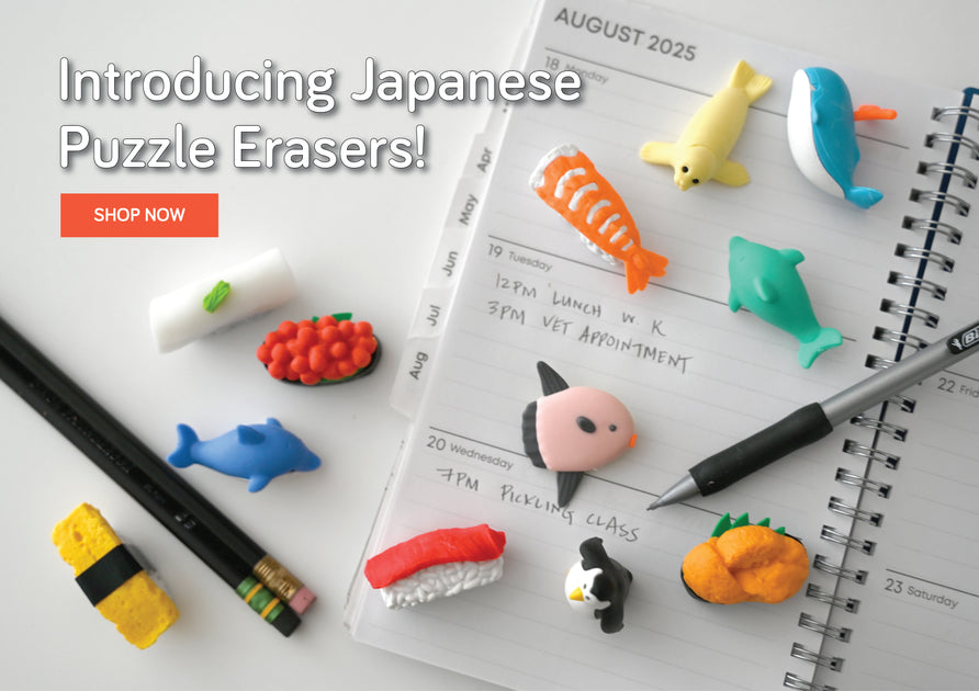 Japanese puzzle erasers scattered atop a daily planner. Pencils are also on the planner. Text: Introducing Japanese Puzzle Erasers! Shop Now